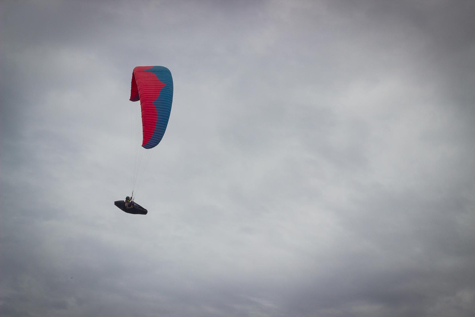 A person flies in a hang glider above a mountain