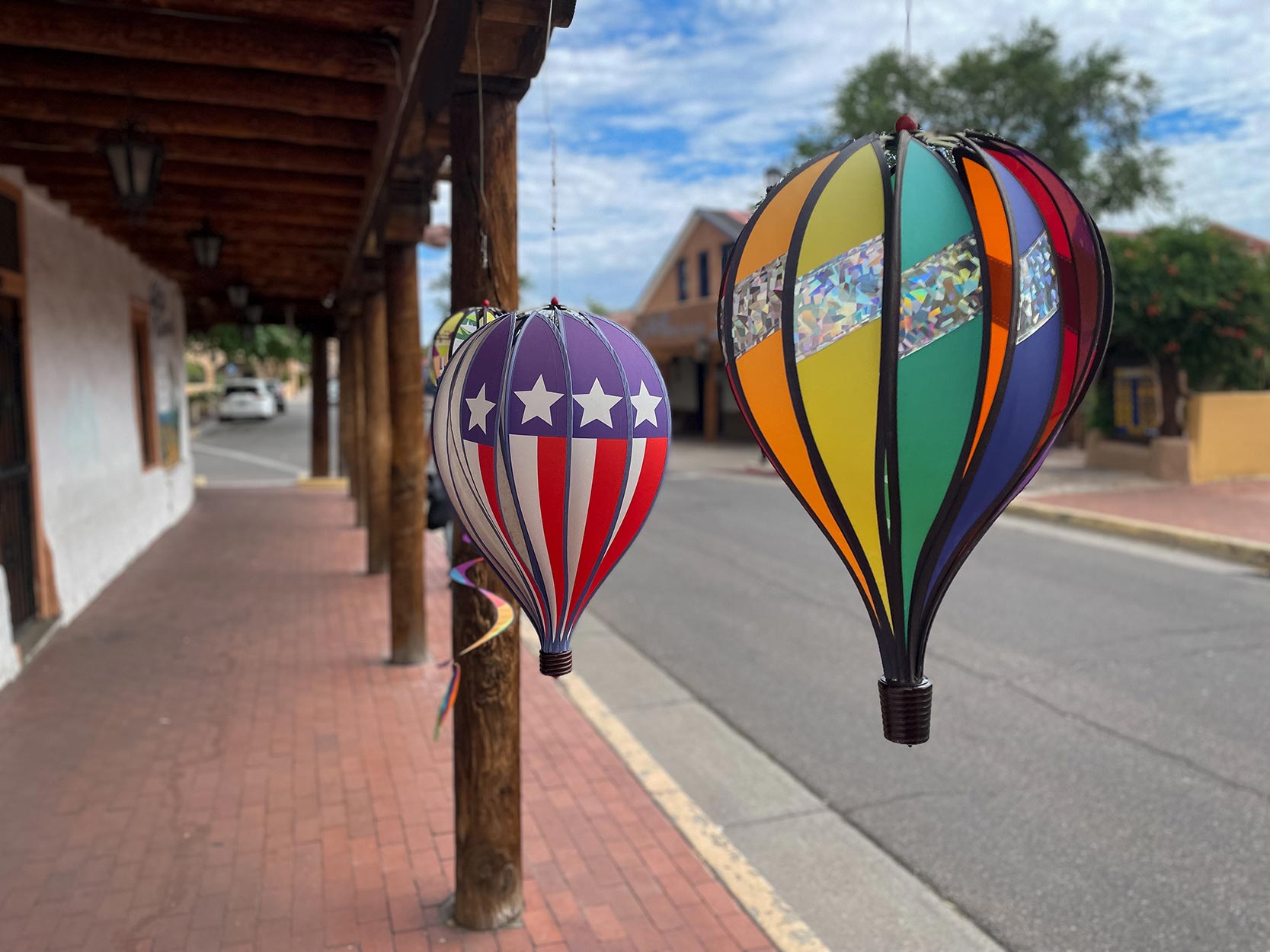 A rainbow-colored balloon and a red, white and blue balloon hang outside a shop