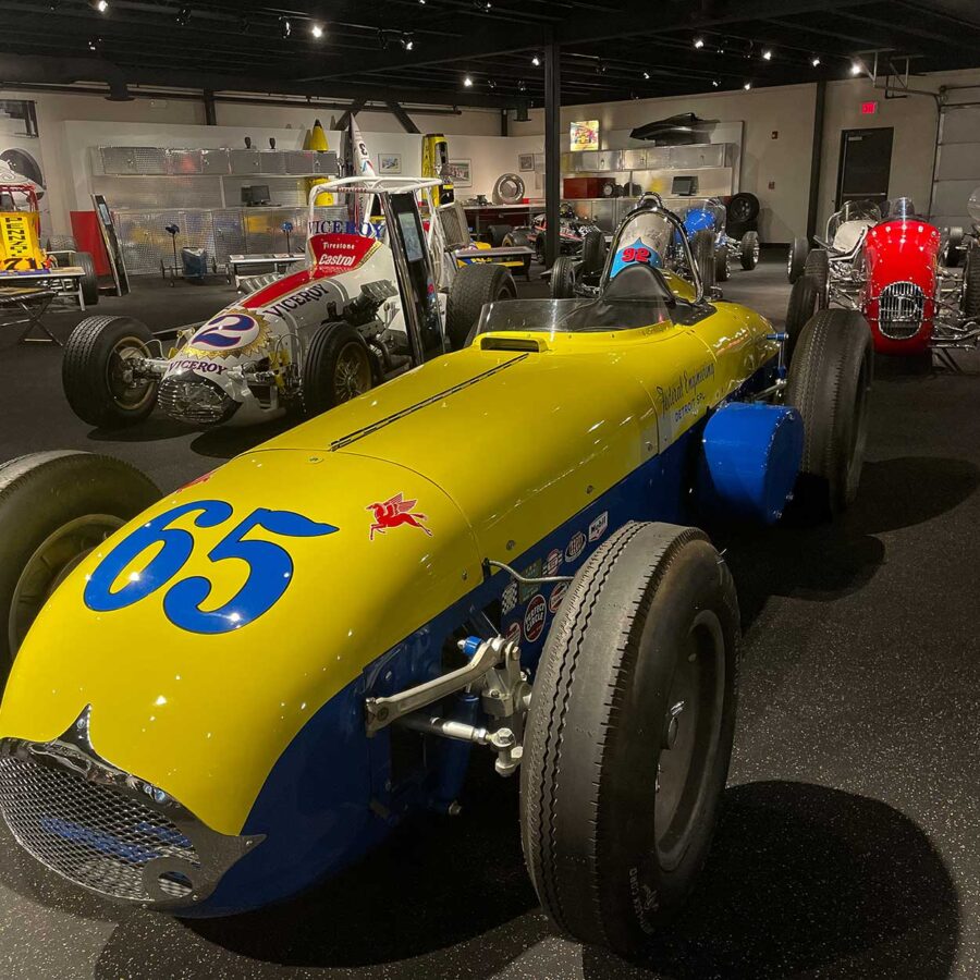 A yellow and blue open wheel race car in a museum